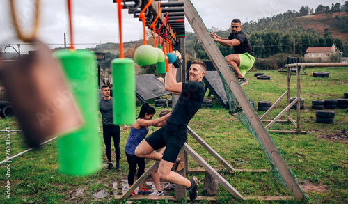 Male participant in an obstacle course doing suspension exercises photo