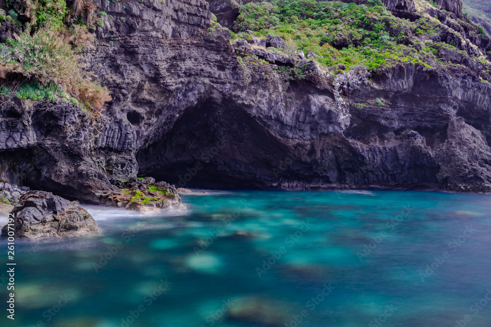 Cave eroded by the Atlantic ocean power, El Sauzal volcanic coastline, long exposure photography with sunlight, Tenerife, Canary islands, Spain
