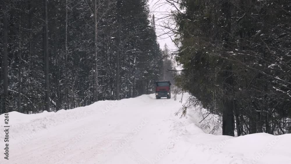 A truck carrying ore rides along a narrow winter forest road. Slow motion. A truck carrying ore rides along a narrow winter forest road. Slow motion.