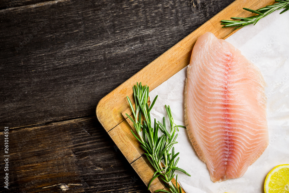 Raw tilapia fish fillet on the cutting board. Selective focus. Shallow depth of field. Raw tilapia fish fillet on the cutting board. Selective focus. Shallow depth of field.