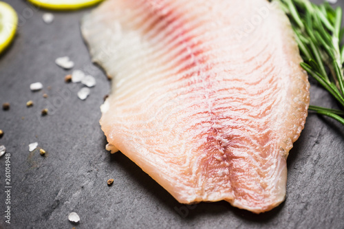 Raw tilapia fish fillet on the cutting board. Selective focus. Shallow depth of field.