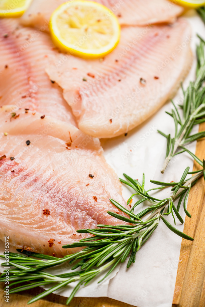Raw tilapia fish fillet on the cutting board. Selective focus. Shallow depth of field. Raw tilapia fish fillet on the cutting board. Selective focus. Shallow depth of field.