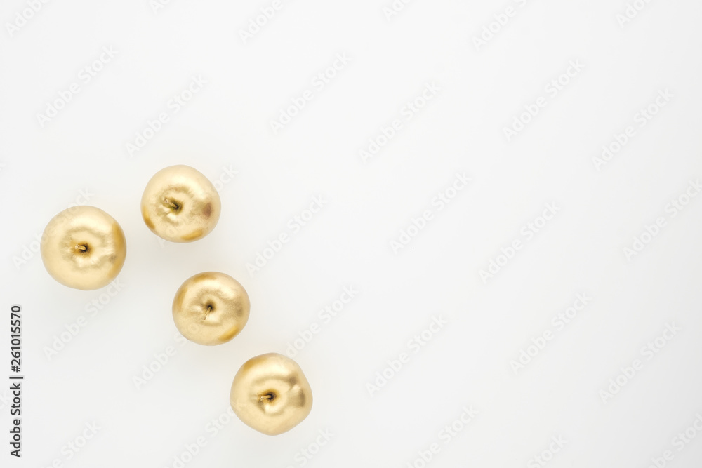 A group of seven gold painted metallic paint apples on a white background. A group of seven gold painted metallic paint apples on a white background.