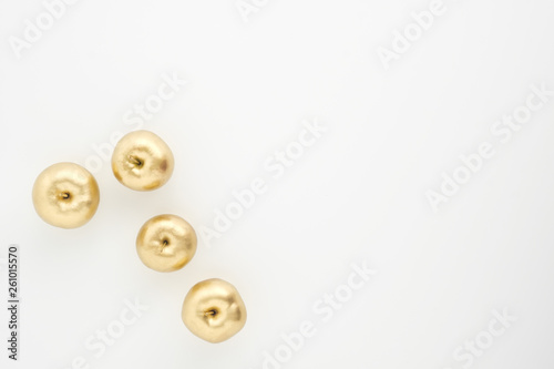 A group of seven gold painted metallic paint apples on a white background.