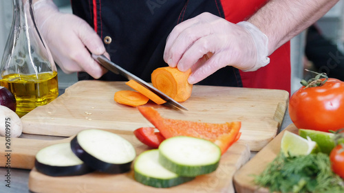 A chef working in the kitchen. Cutting the carrot