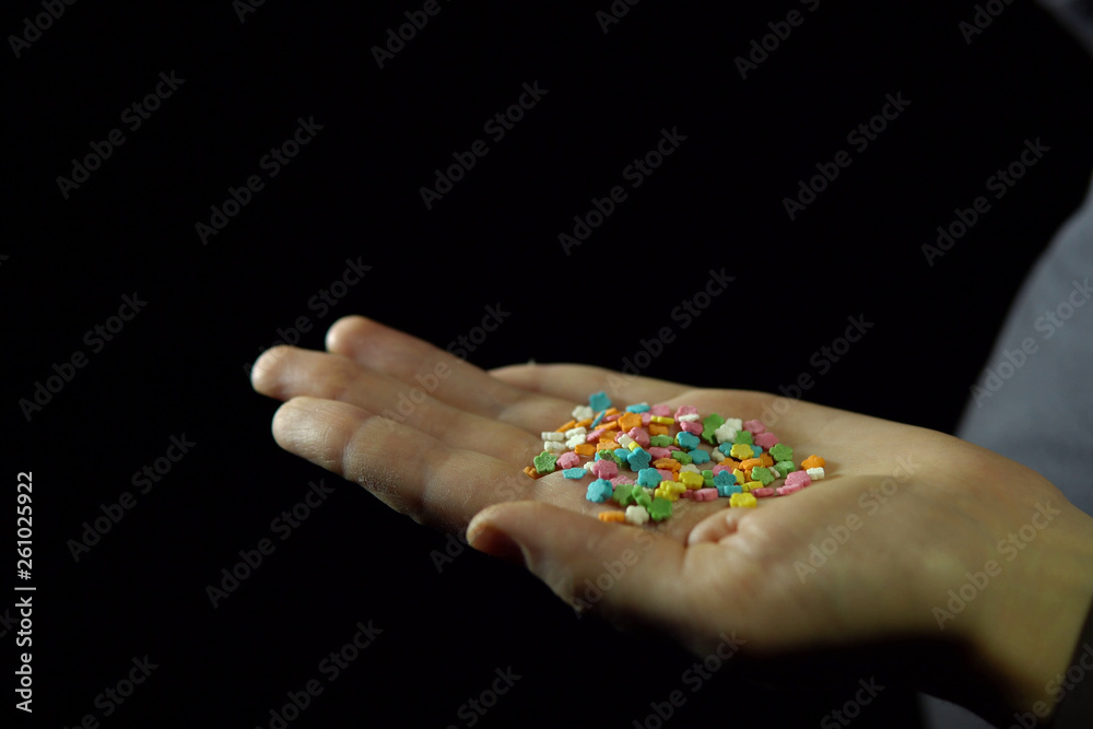 Confectionery powder in a human hand on a black background.