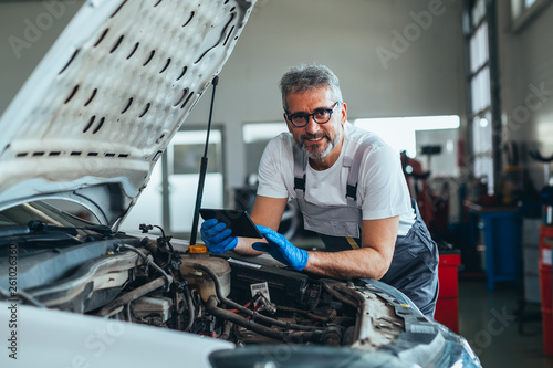 checking online for car spare parts . worker using tablet in car workshop