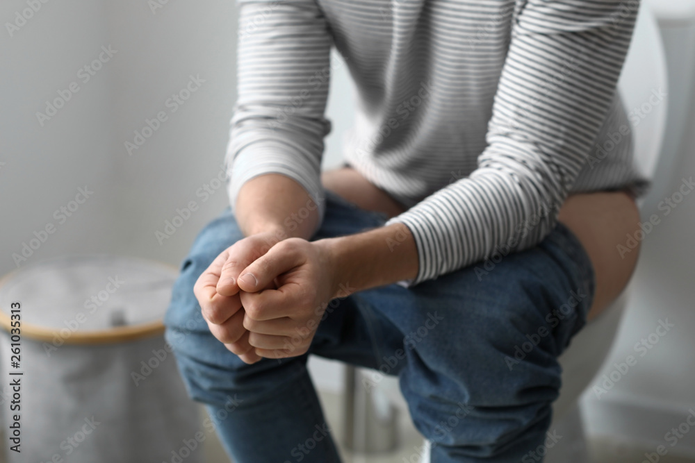 Man sitting on toilet bowl at home