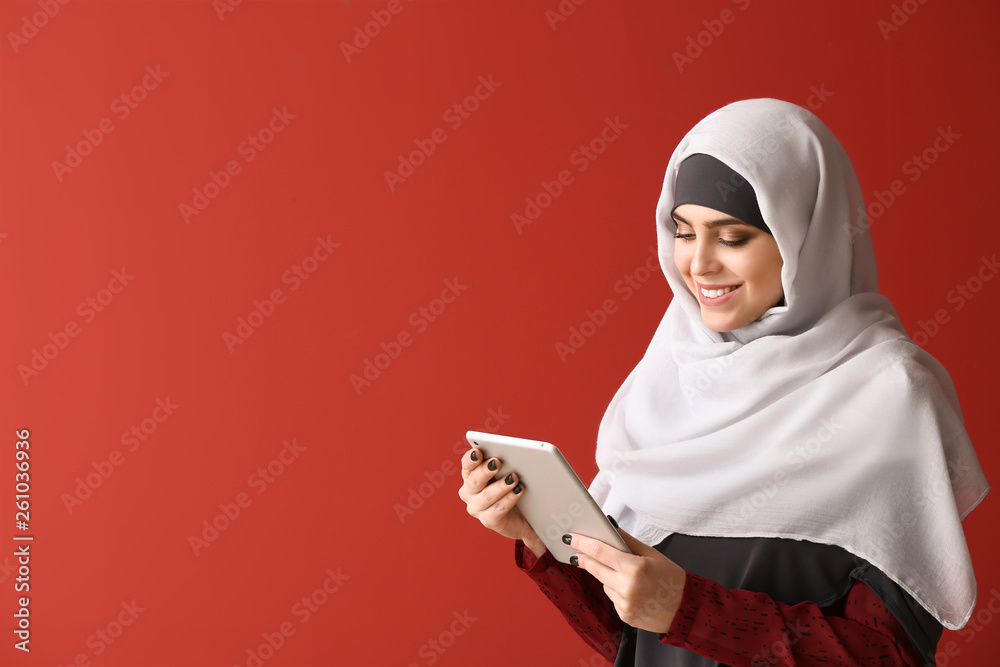 Muslim woman with tablet computer on color background Muslim woman with tablet computer on color background