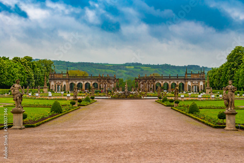 The lovely walkway to the Baroque garden of Weikersheim Palace, framed by two statues, is leading to the beautiful Hercules Fountain in the middle and the picturesque orangery in the background. photo