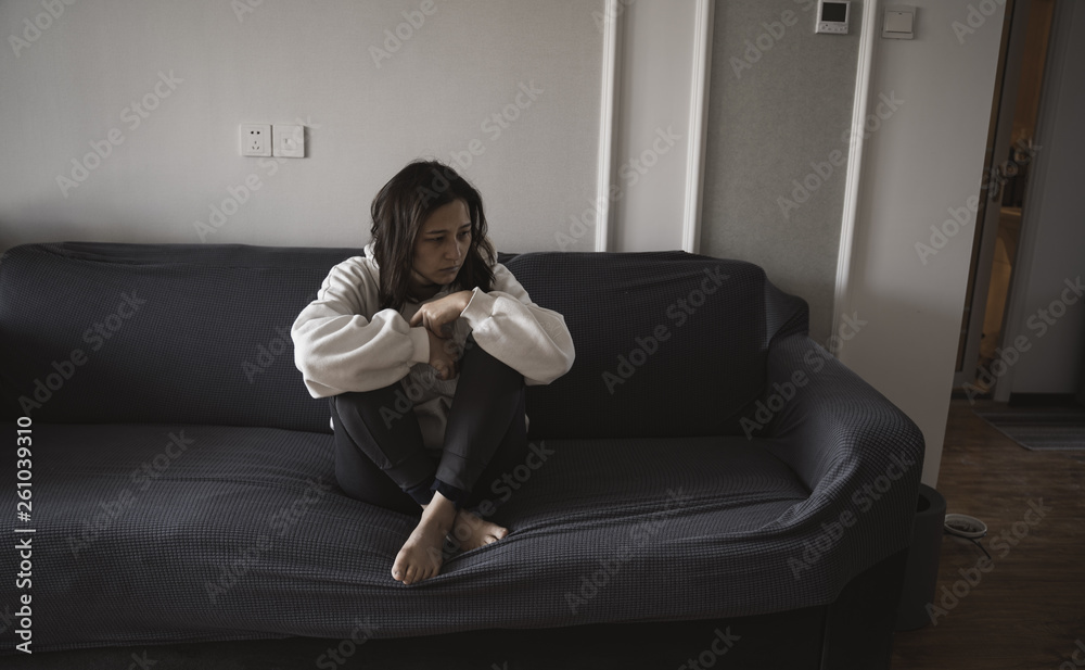 young beautiful just married Asian woman crying on the sofa suffering from domestic violence. young beautiful just married Asian woman crying on the sofa suffering from domestic violence.