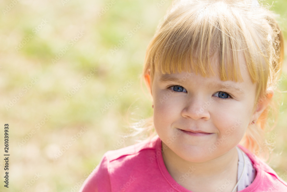 little cute girl smiles and looks into the camera in a city park little cute girl smiles and looks into the camera in a city park