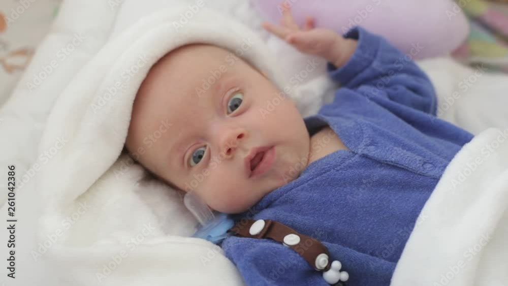 the newborn is lying in the crib and not sleeping. the newborn is lying in the crib and not sleeping.