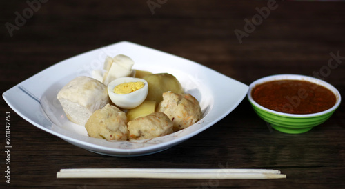 Siomay (fish cake dumplings) and peanut sauce on wood background. 