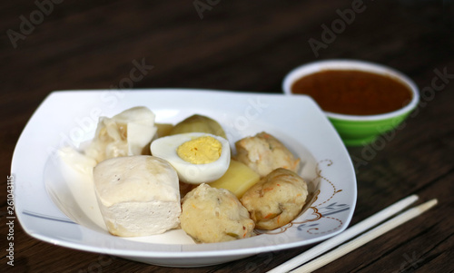 Siomay (fish cake dumplings) and peanut sauce on wood background. 