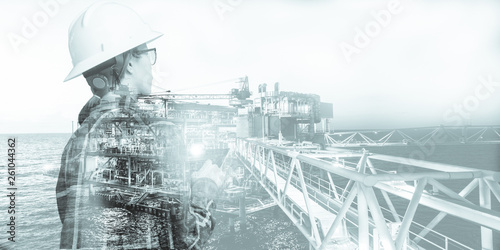 Double exposure of Engineer or Technician woman with safety helmet operated platform or plant by using tablet with offshore oil and gas platform background for oil and gas business concept