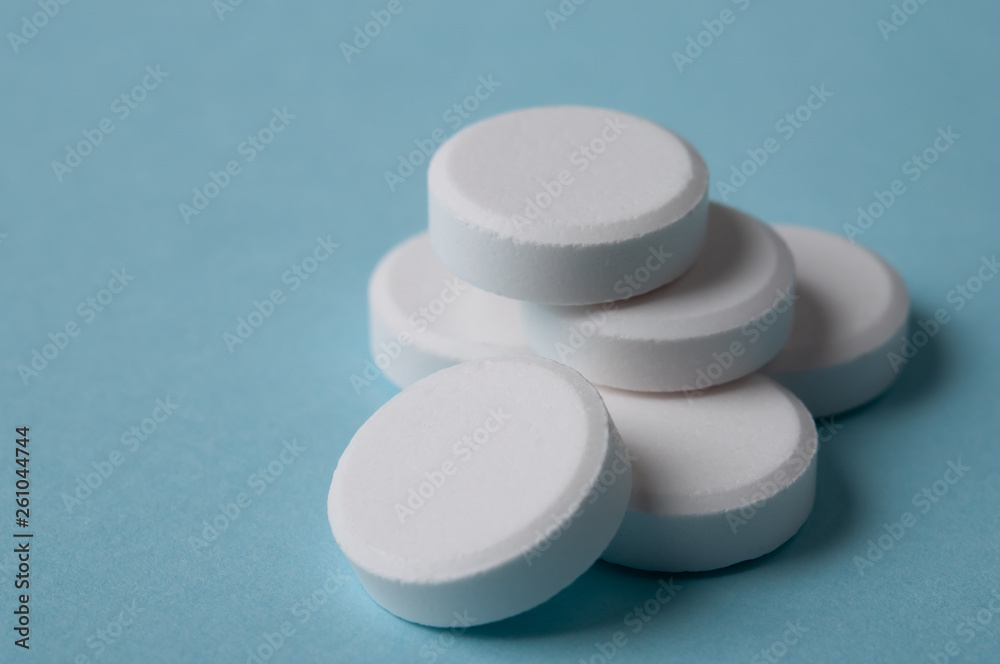white pills on blue background; medical treatment and pharmaceutical industry concept white pills on blue background; medical treatment and pharmaceutical industry concept