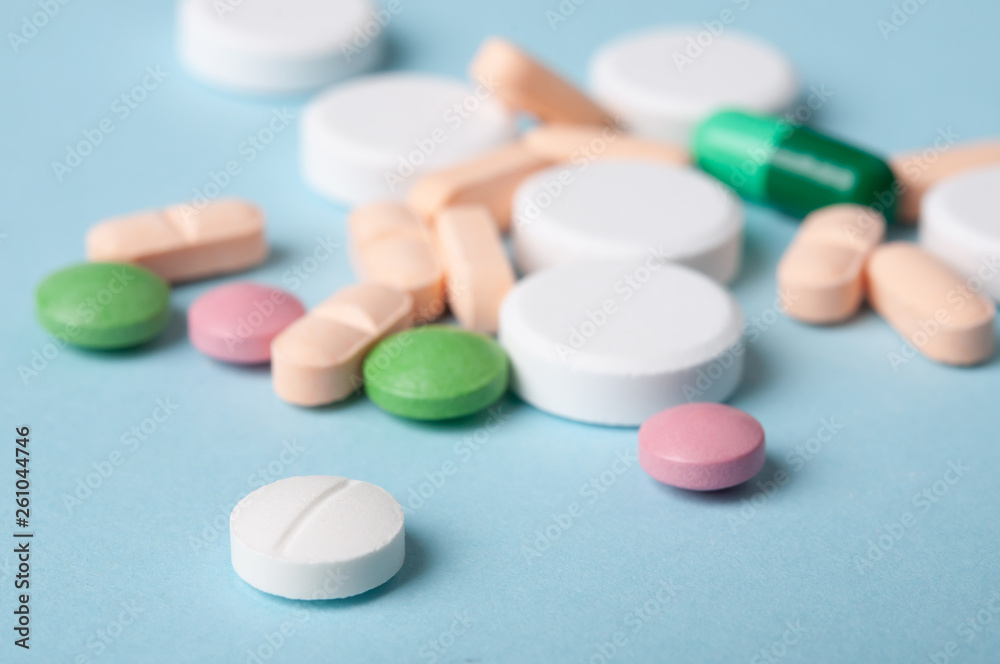 various pills, small tablets of medicine and capsules on blue background; safe drug use concept. . selective focus various pills, small tablets of medicine and capsules on blue background; safe drug use concept. . selective focus
