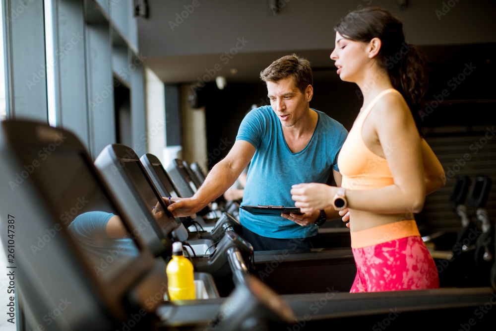 Close up of woman with trainer working out on treadmill in gym Close up of woman with trainer working out on treadmill in gym
