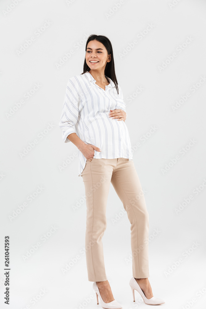 Full length photo of attractive pregnant businesswoman 30s smiling and touching her big tummy Full length photo of attractive pregnant businesswoman 30s smiling and touching her big tummy