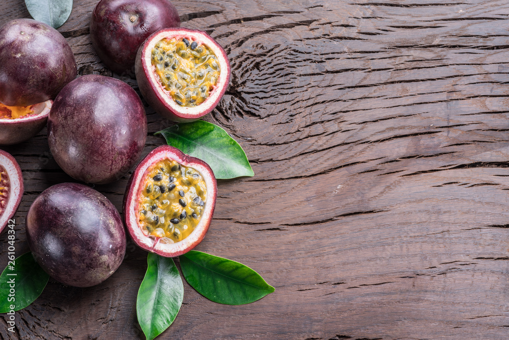 Passion fruits and its cross section with pulpy juice filled with seeds. Wooden background.