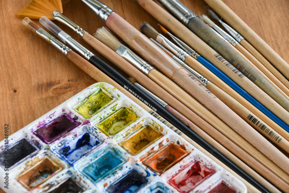 Obraz premium Colorful watercolor, acrylic paints and set of different brushes on wooden boards, closeup.