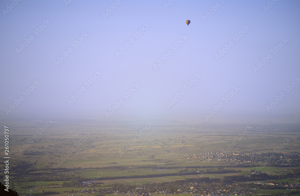 Hot air balloon above the green field and villages Hot air balloon above the green field and villages