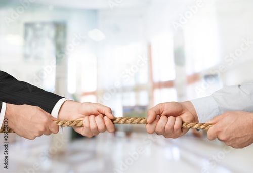 Business people pulling rope in opposite directions at office