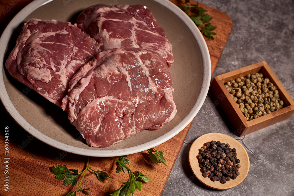 pork cheeks on a plate on a wooden board and next to different spices pork cheeks on a plate on a wooden board and next to different spices