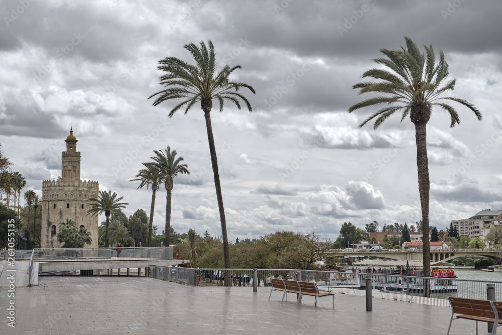 April 2019 - Seville Spain - View along the river in Seville with modern Tower and palms on the background in a cloudy day.