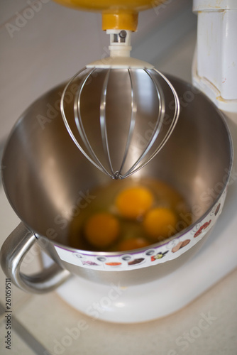 Kitchen front with planetary mixer with egg whites and yolks in a metalic bowl waiting to be stirred. Electrical kitchenware ustensil used to prepare delicious desserts and glourious recipes. photo