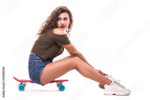Smiling pretty woman sitting on the skateboard isolated on white background