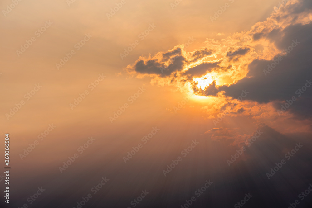 Golden sun rays from a peaceful sunset in a partly cloudy sky