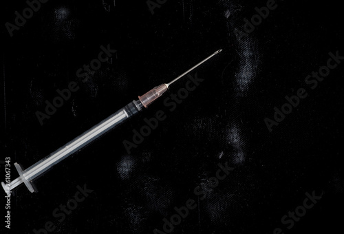 injection syringe with a needle on a dirty black background
