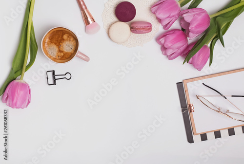 Beautiful pink tulips, cup of coffee and macarons on the white table