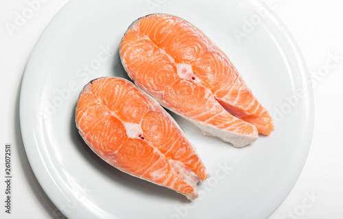 Two steaks of fresh salmon on a white plate. Raw red fish steak. Delicacy. Photos for sale of salmon and trout.