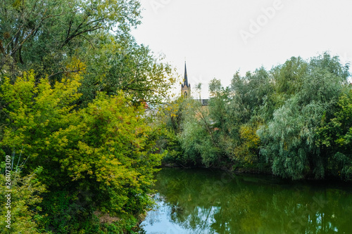 An ancient church between the trees near the river Styr in Lutsk in Ukraine. Autumn morning.