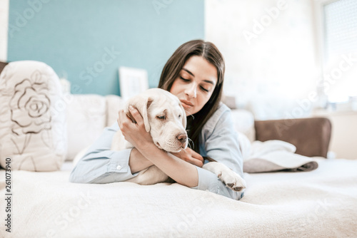 Beautiful young woman cuddles and hugs her best friend puppy dog.