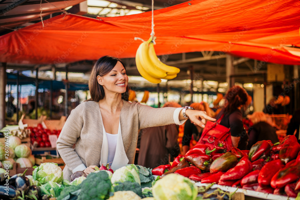 Young woman buying vegetables at market.