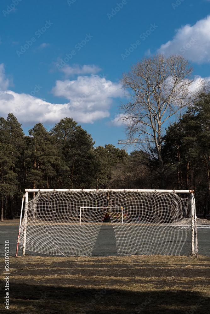 Old soccer goal with a torn net. Empty football field with gates. Old soccer goal with a torn net. Empty football field with gates.