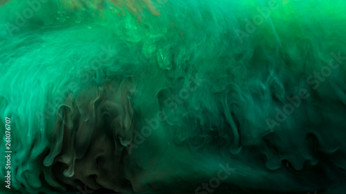 Bright emerald ink in water. Spectacular drops in green ink on a dark background.