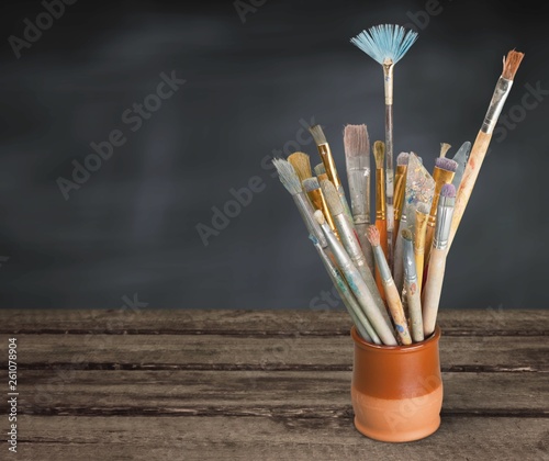 Brushes in a glass jar on the table and white wall