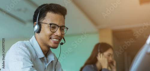close up asian man call center agent wear headset device and smiling working in operation room with service-mind at  desktop table , telemarketing and help desk concept
