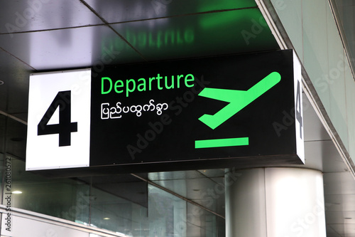 Departure sign in english and Myanmar language with symbol of the plane take off in green on black color at the gate number 4.
