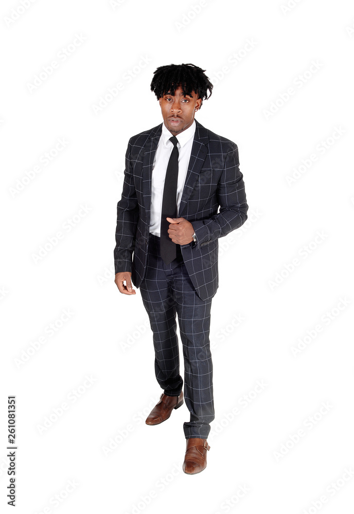 Black man in a dark suit standing in the studio with fussy black hair Black man in a dark suit standing in the studio with fussy black hair