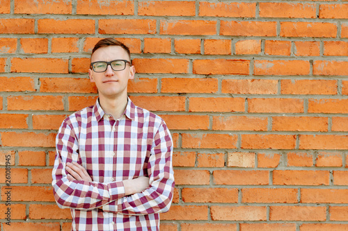 Portrait of a guy in a shirt and glasses against a brick wall