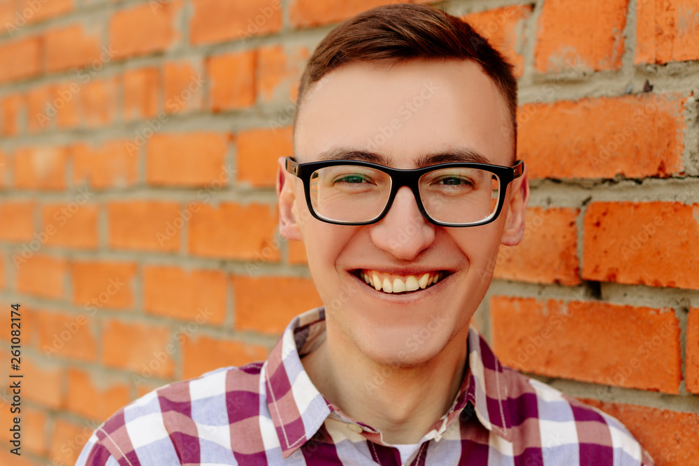 Portrait of a guy in a shirt and glasses against a brick wall Portrait of a guy in a shirt and glasses against a brick wall