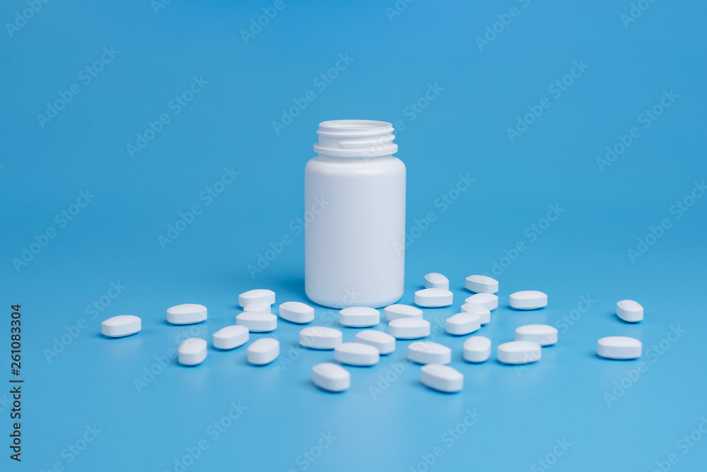 White pills, tablets and white bottle on blue background White pills, tablets and white bottle on blue background