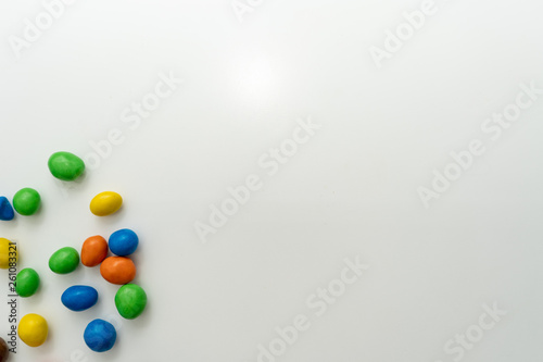 Multicolored candies (dragees) in the glaze scattered on a white background. Place for text