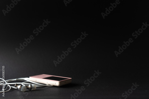 Portable music pink player and earphones on a black background. Place for text